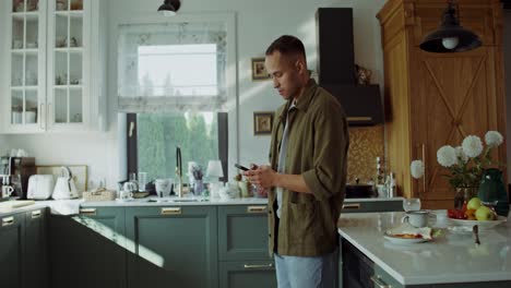 man using smartphone in kitchen