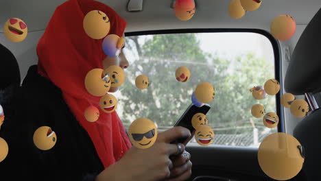 emojis de cara que se mueven contra la mujer en hijab usando un teléfono inteligente en un coche