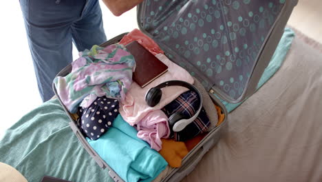 A-mature-Caucasian-woman-closing-her-suitcase,-smartphone-nearby