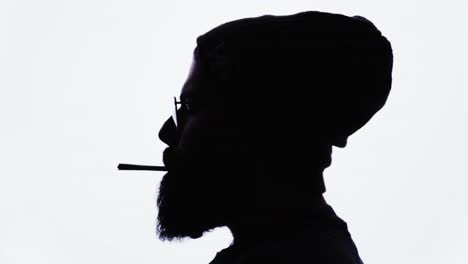 silueta de hombre barbudo encendiendo marihuana, fumando y exhalando, fondo blanco, cannabis