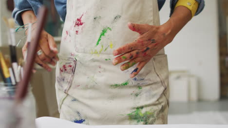 artist shows off paint-covered hands in a creative studio