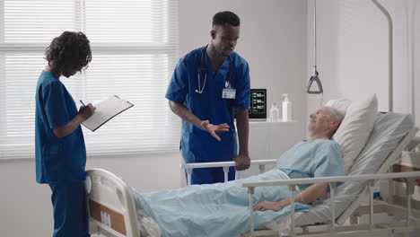 two black doctors are talking to a patient lying in a hospital room