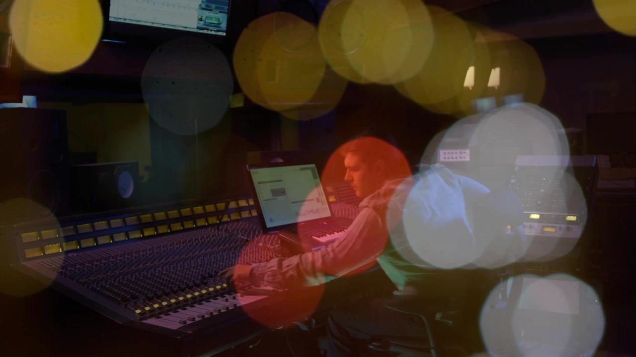 Playback starting, engineer adjusting faders and checking laptop while mixing, bokeh shifting