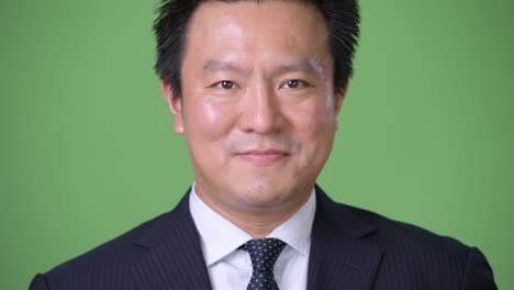 hombre de negocios japonés maduro contra un fondo verde