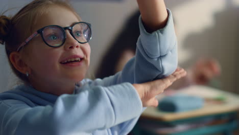 Schoolgirl-learning-in-classroom.-Female-pupil-raising-hand-during-lesson