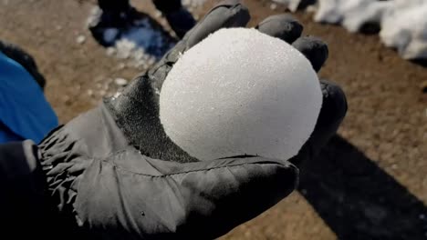 rolling big snowball in gloved hand in slow motion