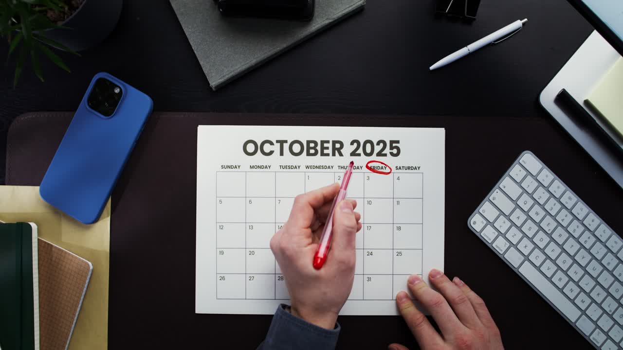 Persona che segna le date sul calendario di ottobre 2025