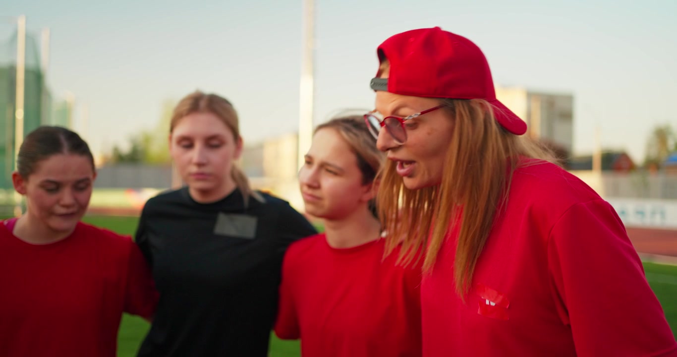 Entrenadora instruyendo a jóvenes atletas en un campo deportivo