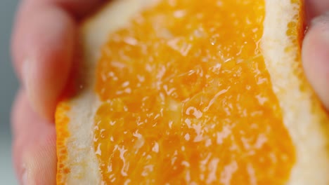 person squeezing orange with juice droplets spraying in air