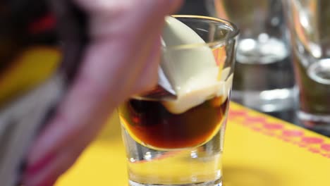 pouring irish cream through the back of a cold spoon into a shot glass with coffee liqueur