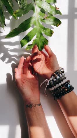 hands with bracelets and a green leaf