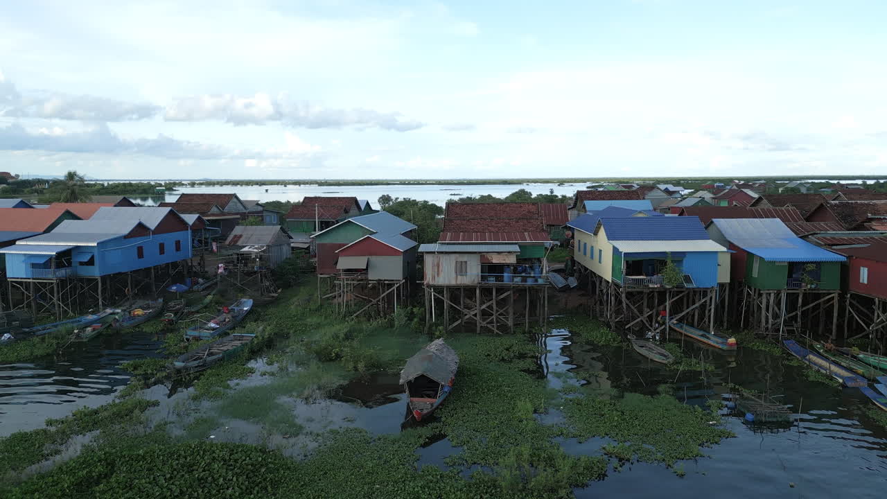 Aerial video of colorful stilt houses at Tonlé Sap, their rooftops in bright reds, blues, and greens, standing above the water on wooden stilts