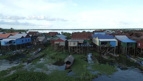 aerial video of colorful stilt houses at tonlé sap, their rooftops in bright reds, blues, and greens, standing above the water on wooden stilts