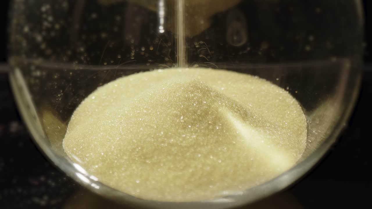 gotas de arena de reloj de arena en la parte inferior de la bombilla de vidrio, concepto de procrastinación. primer plano