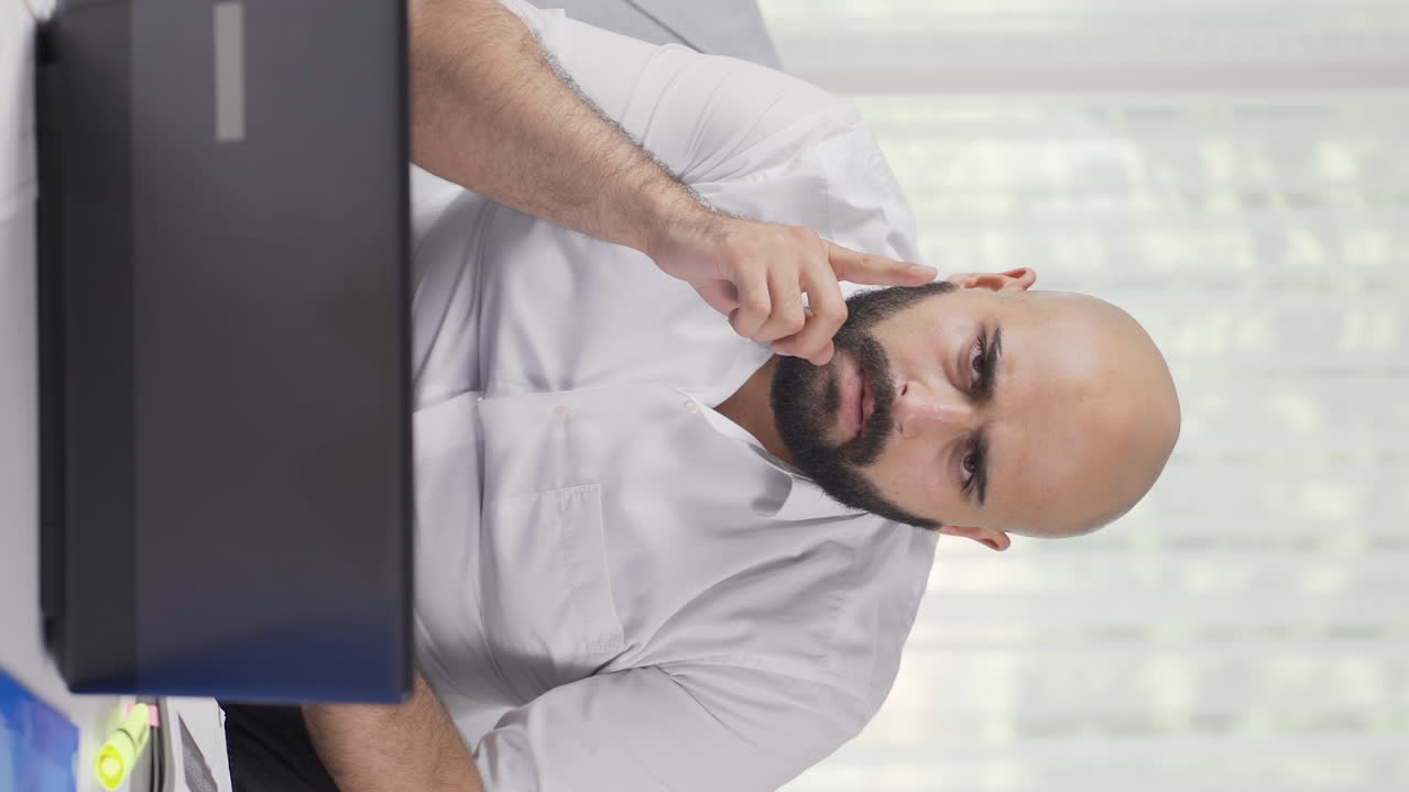 Vertical video of Home office worker man thinking looking at camera.