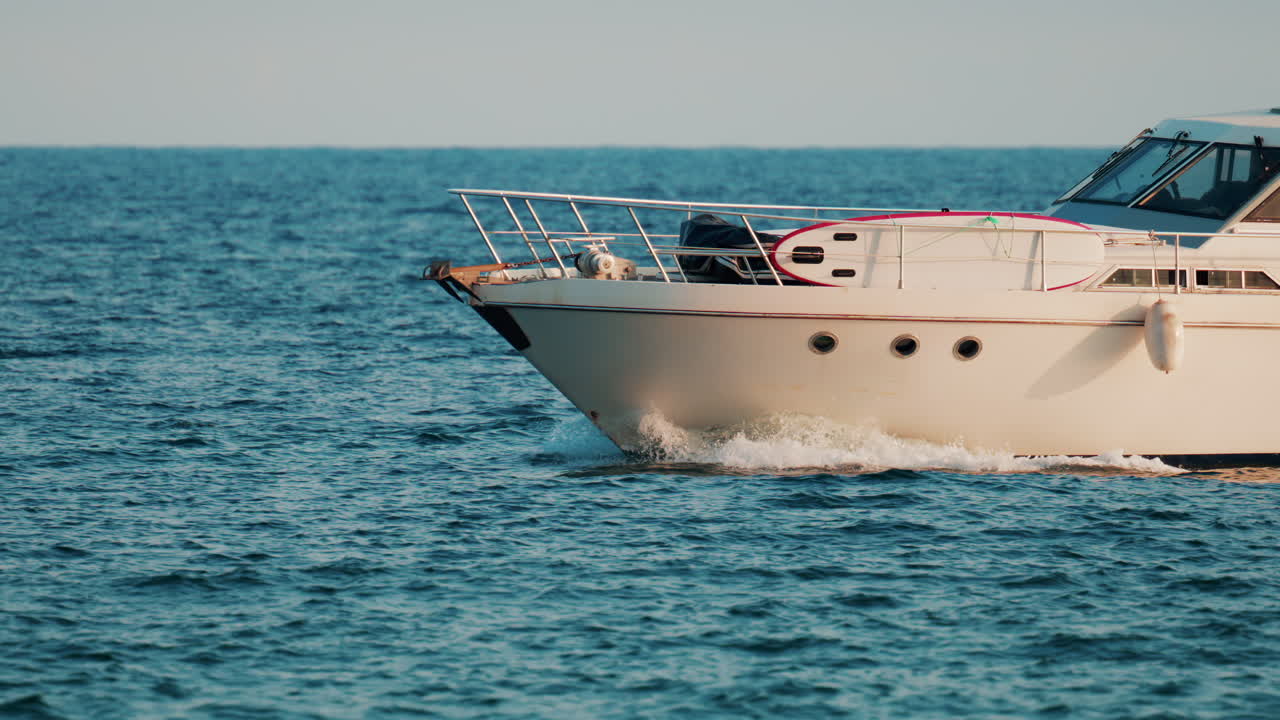 A modern white yacht cruises smoothly across the blue sea under clear skies
