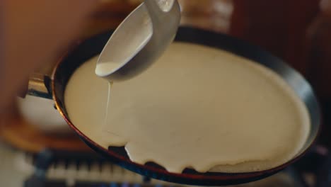 close up of pancake batter being carefully poured into a hot pan and distributed