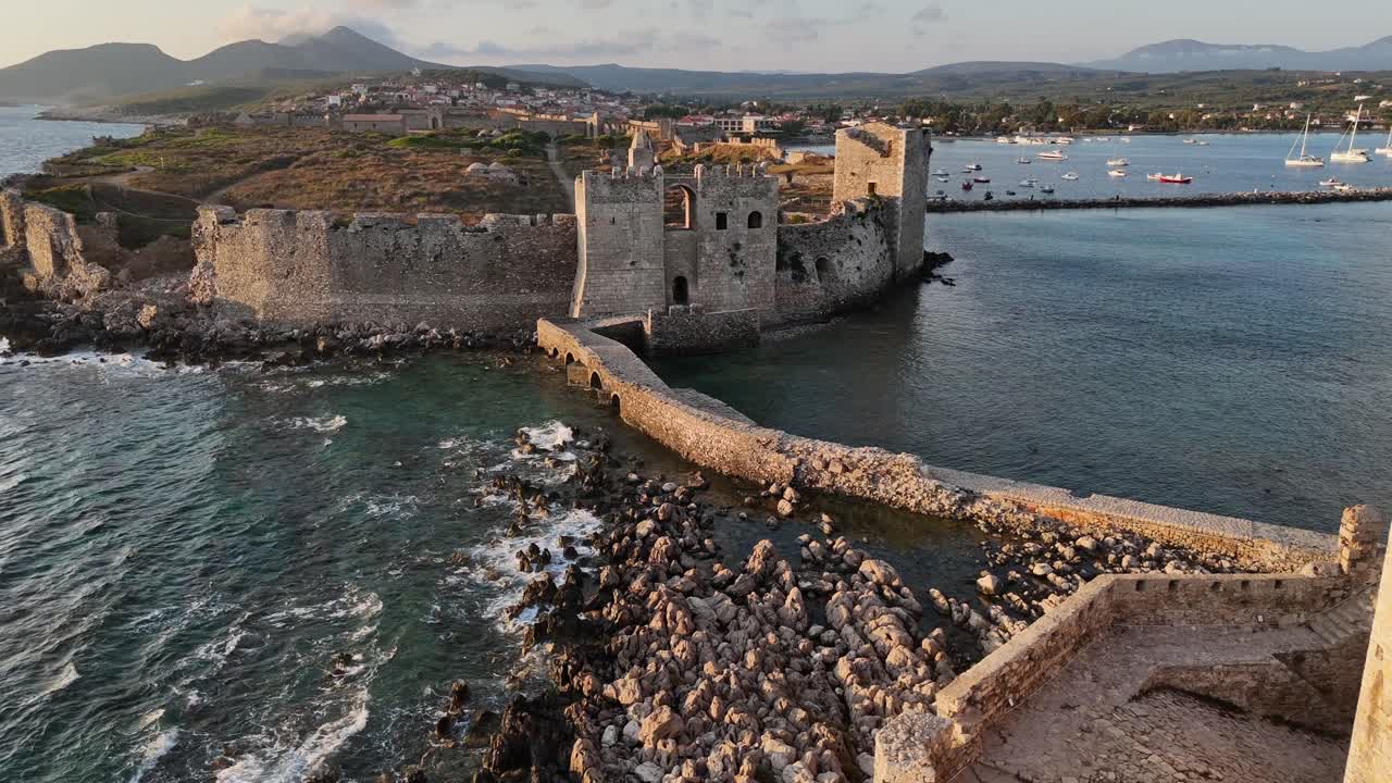 Methoni,Messenia,Peloponnese,Aerial view forward from Bourtzi Tower towards Methoni Castle surrounded by crystal clear waters, Background are hills and beautiful landscape during golden hour