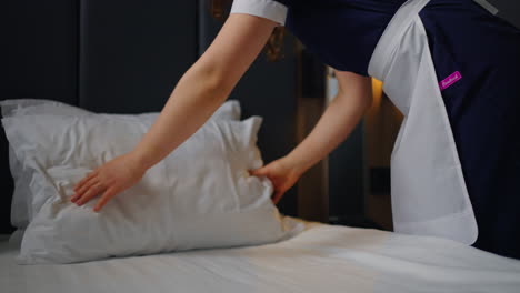 maid making bed in hotel room