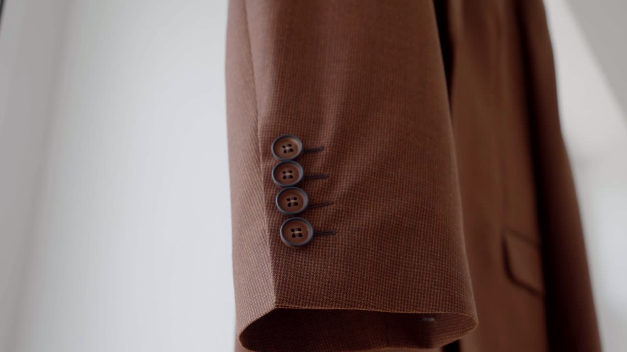 Wedding preparations, a close-up of the cuff buttons on the suit jacket hanging on a hanger, waiting for the groom