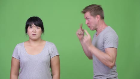 young angry man talking to calm overweight asian woman