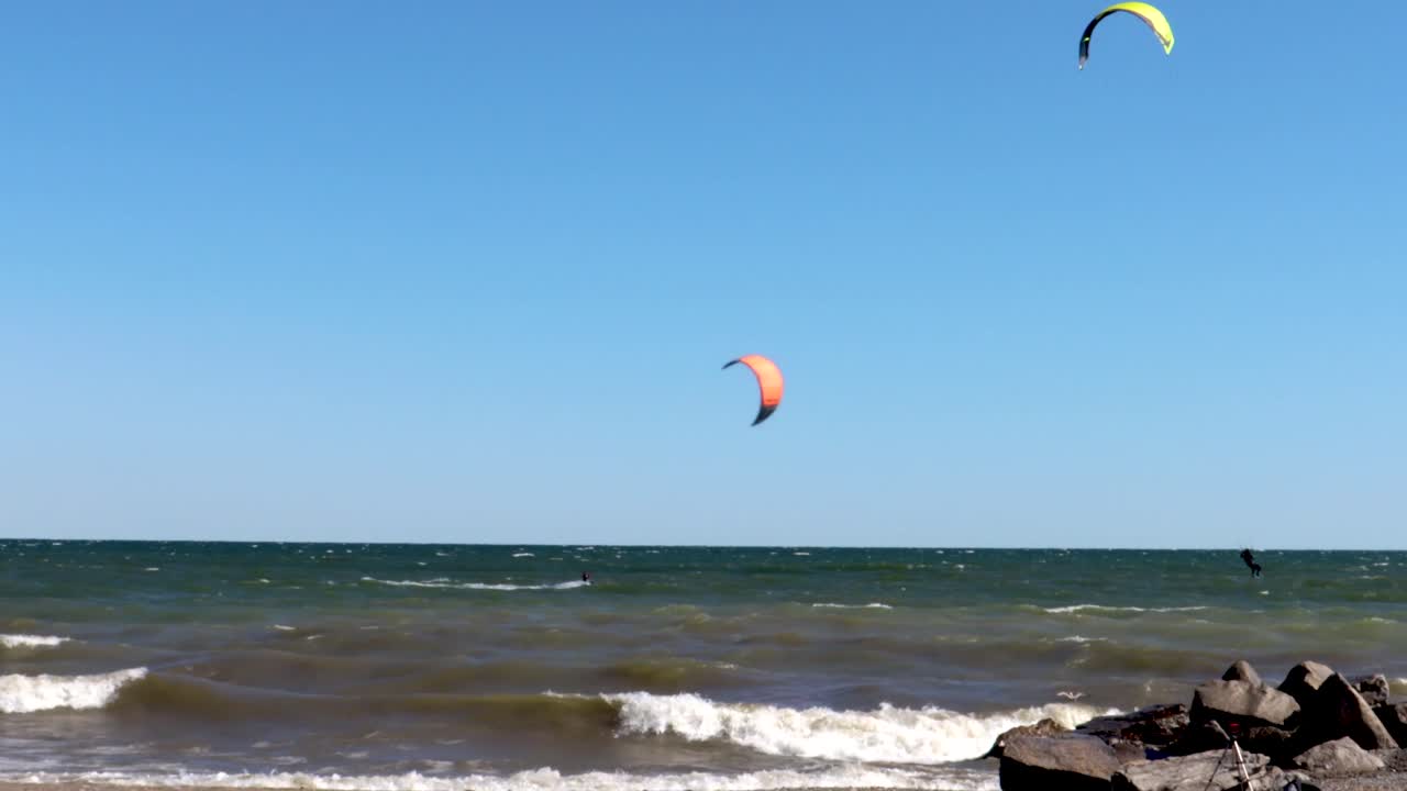 practicantes de kitesurf en un hermoso día prácticamente despejado atravesando la costa