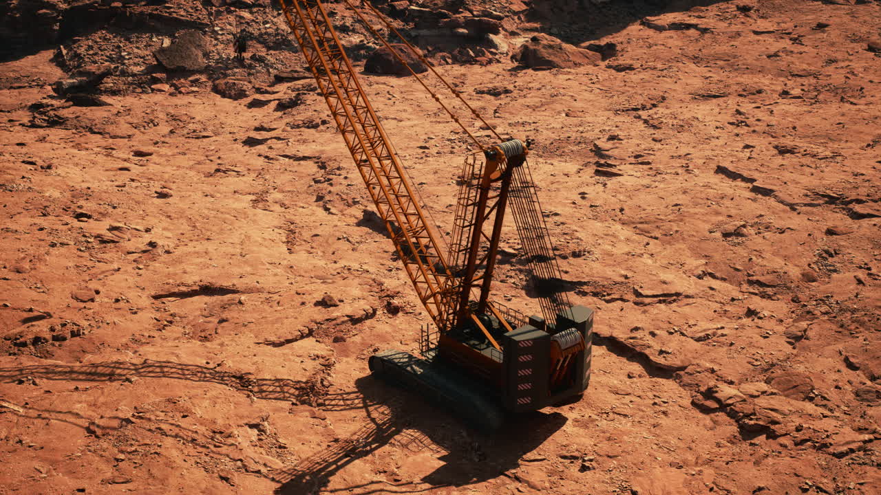 una gran grúa de construcción naranja se sienta en una superficie de tierra y roca, su brazo extendido y el cable colgando hacia abajo