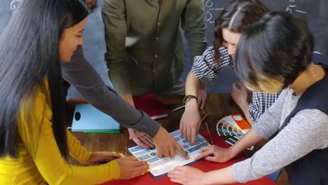 multi-etnische groep jongeren die een project plannen, aan een bureau staan en met elkaar praten 1