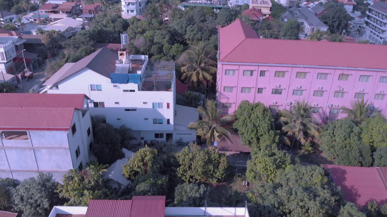 Droneoptagelse i stigende højde fra tropisk hotelgrund og swimmingpool til by