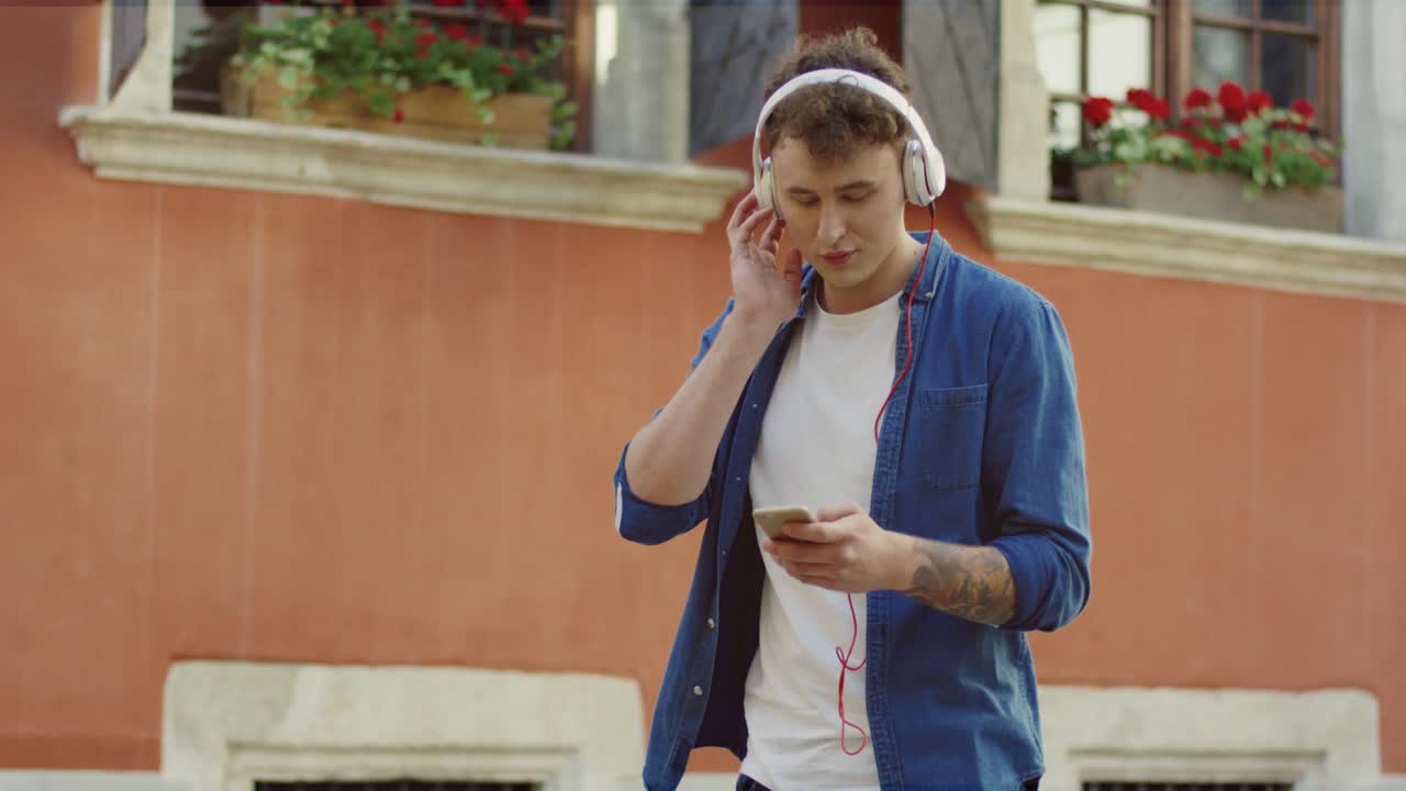 chico elegante escuchando música y caminando por la calle