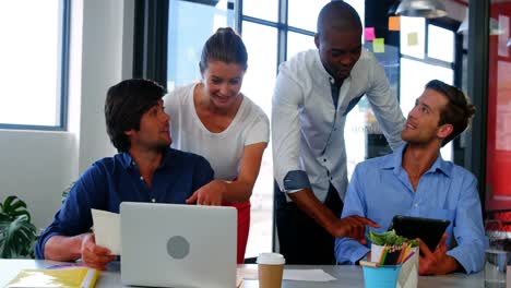 Business-executives-discussing-over-laptop-and-digital-tablet