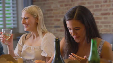 multi-cultural group of friends enjoying drinks and takeaway food at home together