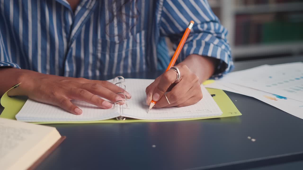 Close up hands ethnic woman left handed who writes something in journal