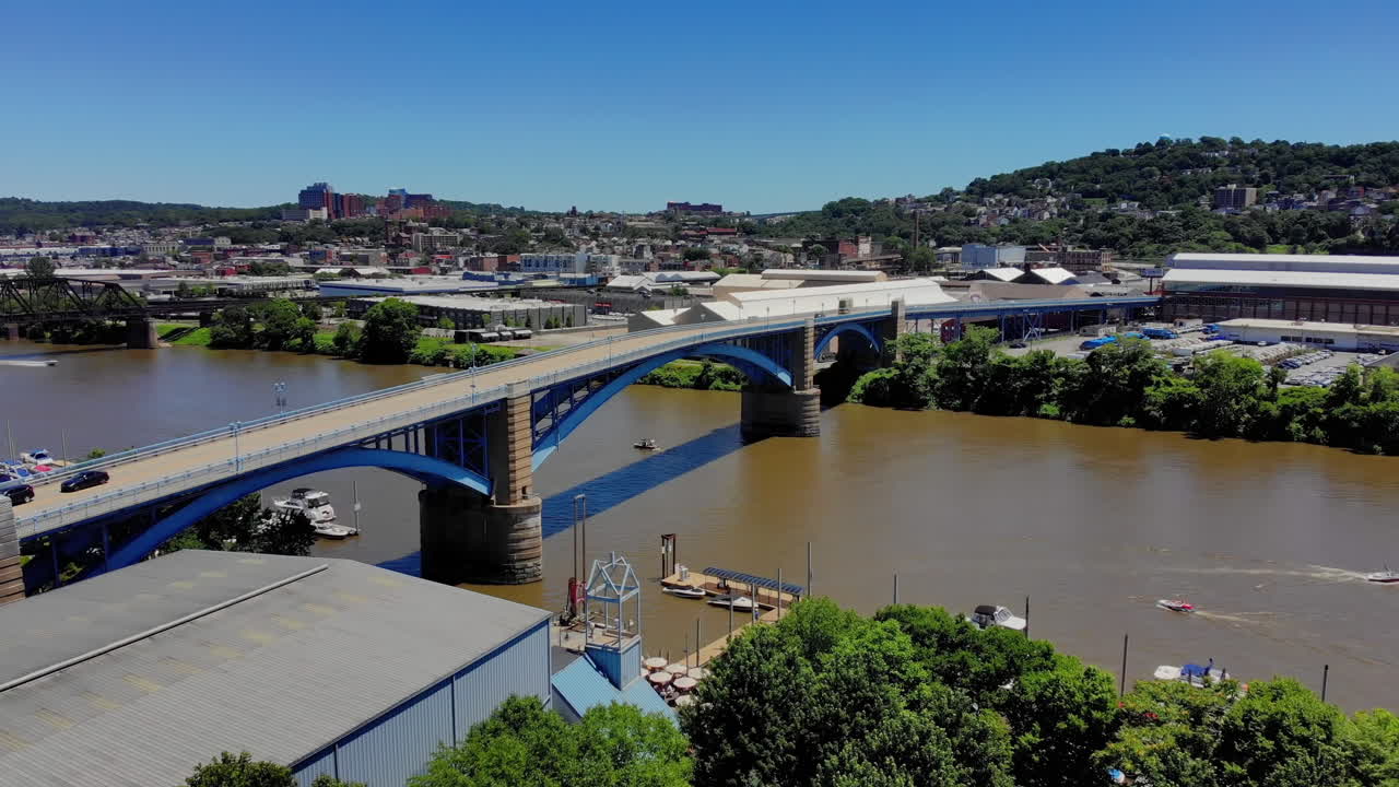 A high angle aerial slow reverse establishing shot of Pittsburgh's 31st Bridge spanning over the Allegheny River between Washington's Landing Island and the Lawrenceville business district.