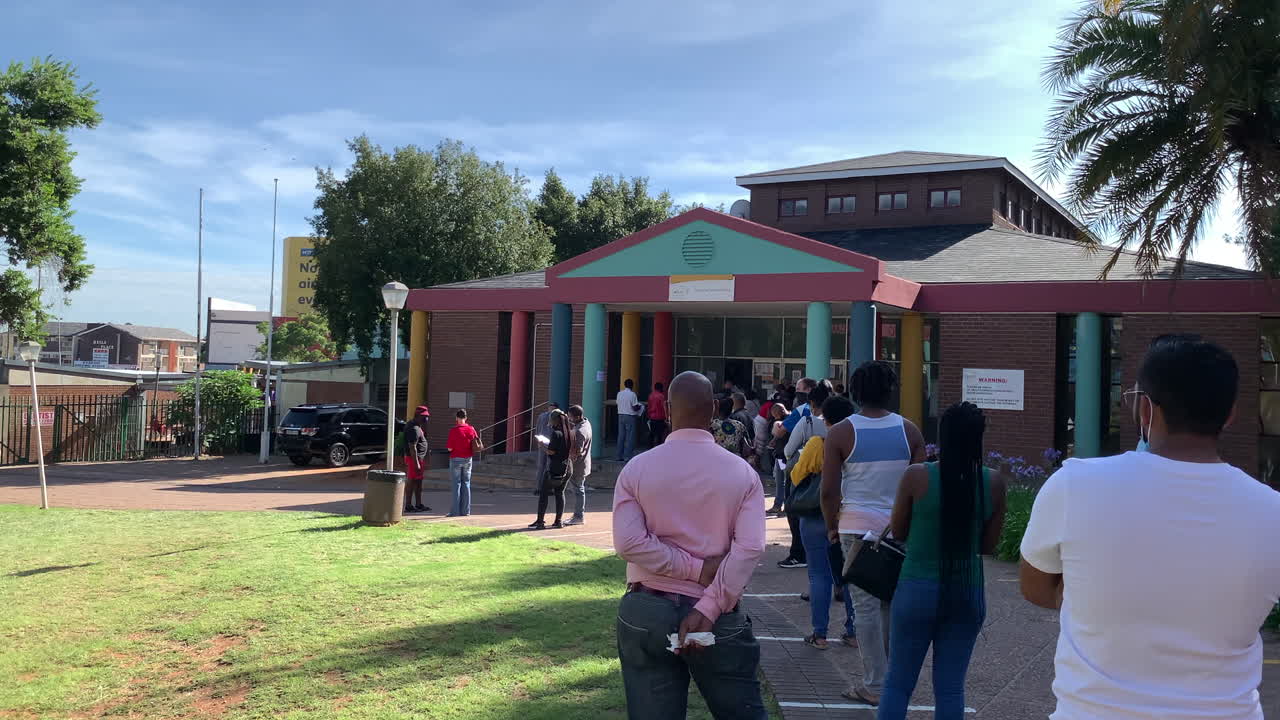 African people standing in line at government building, panning shot left to right