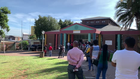 African people standing in line at government building, panning shot left to right