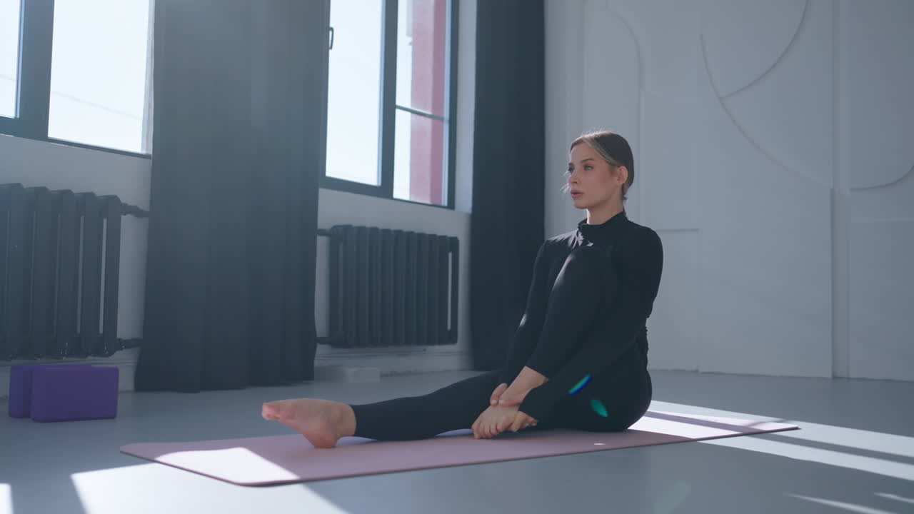 mujer haciendo yoga en una alfombra en un estudio