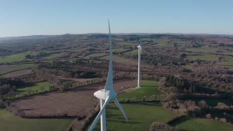 Zwei-Rotierende-Turbinen-Sind-Teil-Eines-Großen-Windparks,-Der-In-Einer-Grünen-Landschaft-Errichtet-Wurde