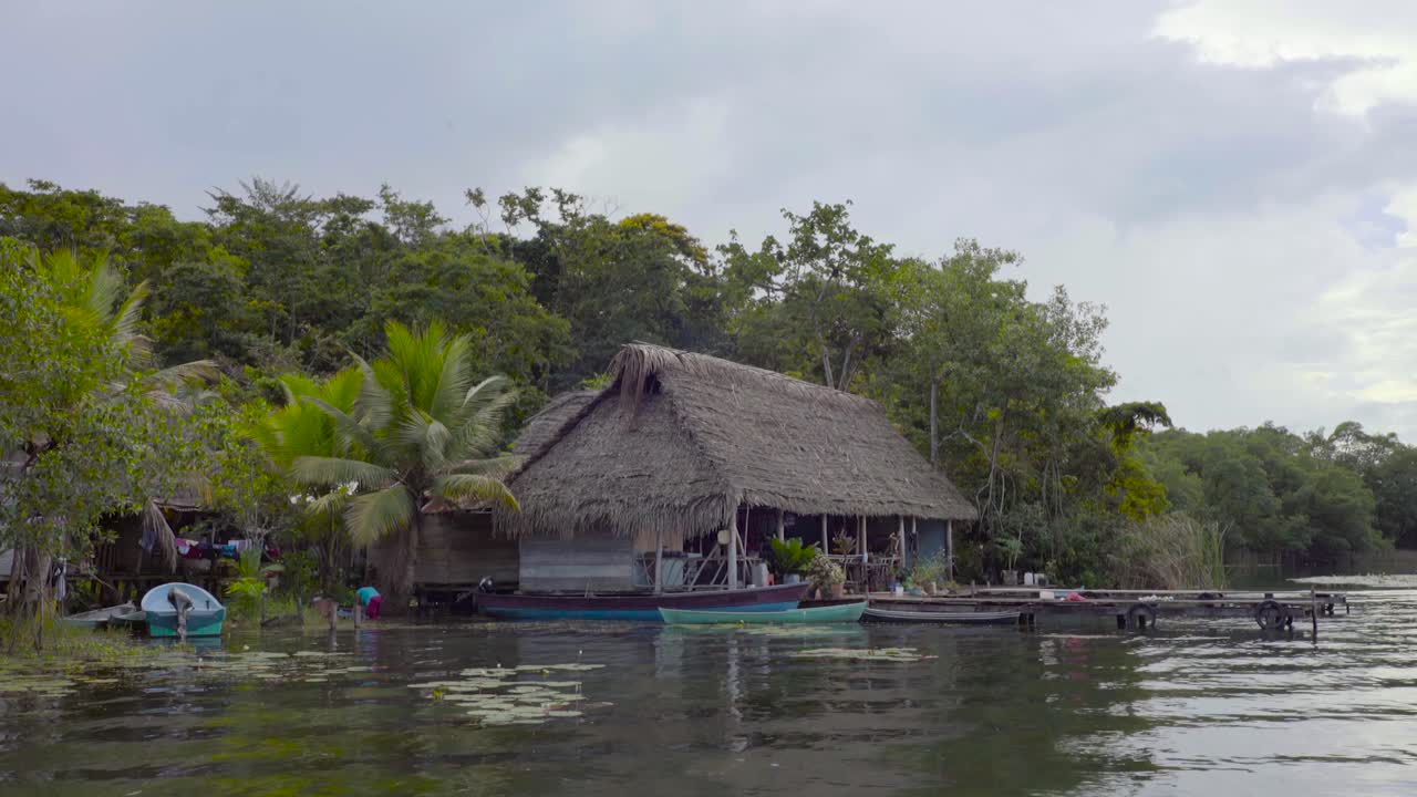 vista desde un bote de chozas de un pueblo sobre pilotes a lo largo de un río en guatemala