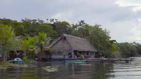 Blick-Von-Einem-Boot-Auf-Ein-Dorf-Hütten-Auf-Stelzen-Entlang-Eines-Flusses-In-Guatemala