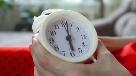 la mujer fija la hora en el despertador a las 6 y fija la alarma para la mañana.