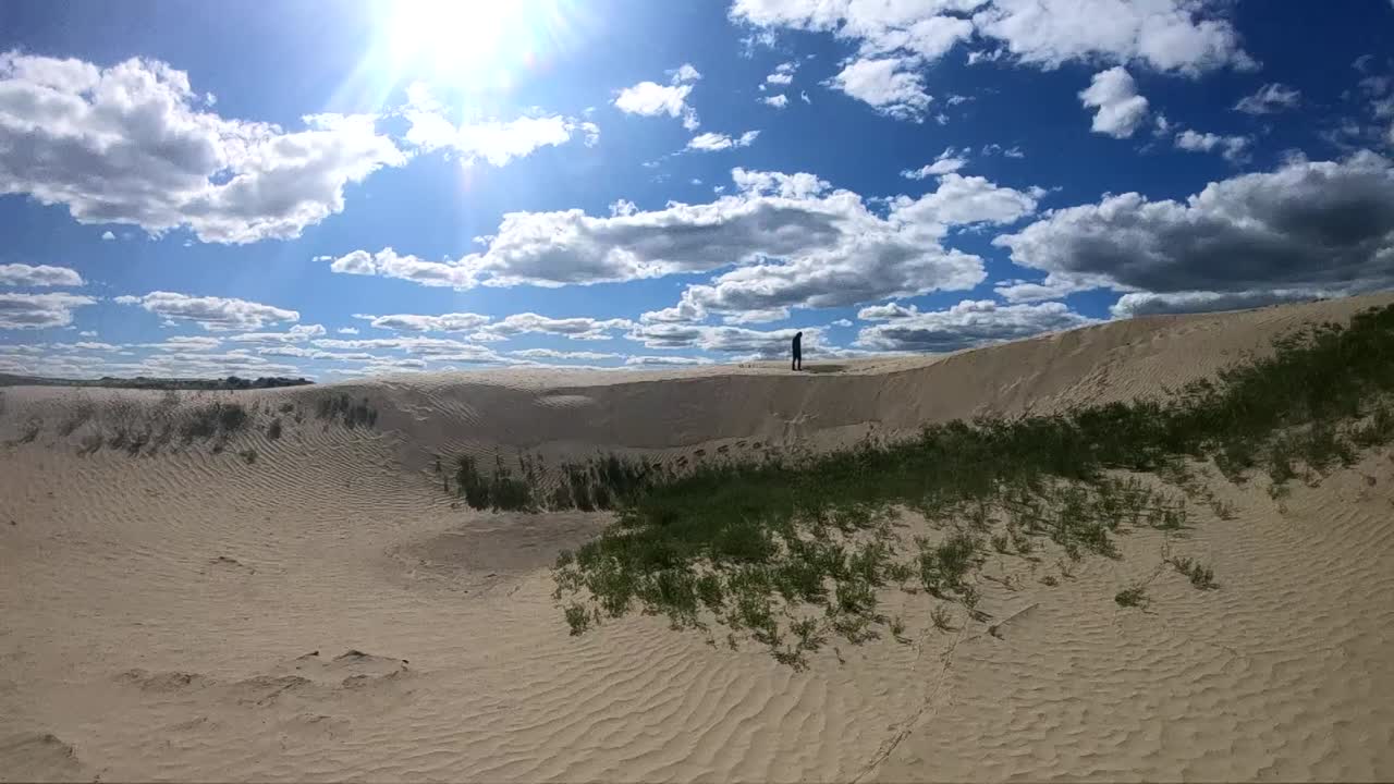 Person standing in the sand in the sand dunes on a sunny day. Filmed in Alberta Canada