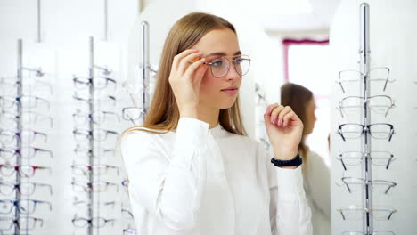 girl choosing glasses in store. woman in optical shop choosing eyeglasses