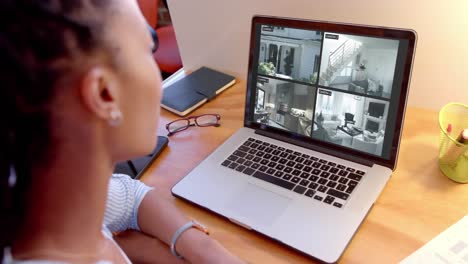 African-american-woman-watching-home-cctv-camera-views-on-laptop,-slow-motion