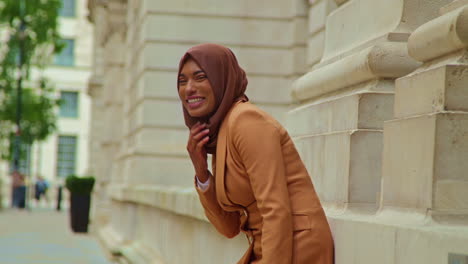 portrait of smiling muslim businesswoman wearing hijab and modern business suit standing outside city office buildings 5