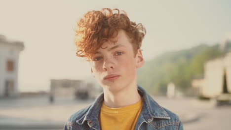 red haired teenager with freckles looks smiling directly into the camera