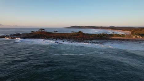 crashing waves on rugged angourie point peninsula with angourie point beach revealed