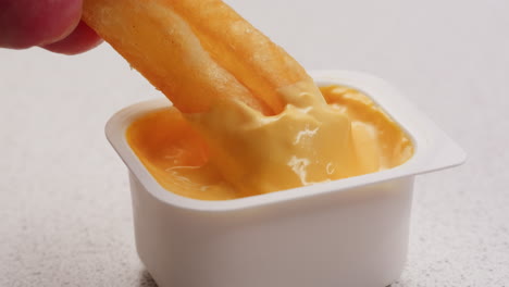 french fries dipping in cheese sauce