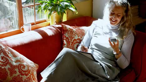 mature woman writing on diary while talking on mobile phone 4k