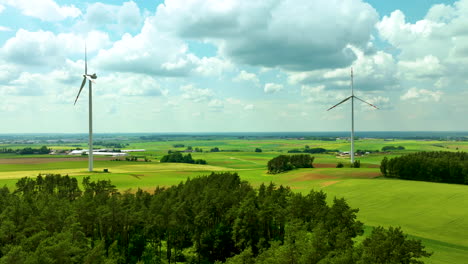 Aerial-footage-featuring-two-wind-turbines-set-in-a-vast,-green-rural-landscape-under-a-partly-cloudy-sky